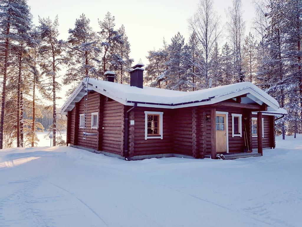 eine kleine Holzhütte mit Schnee auf dem Dach in der Unterkunft Loma-Pälsilä lakeside villa in Kuhmoinen