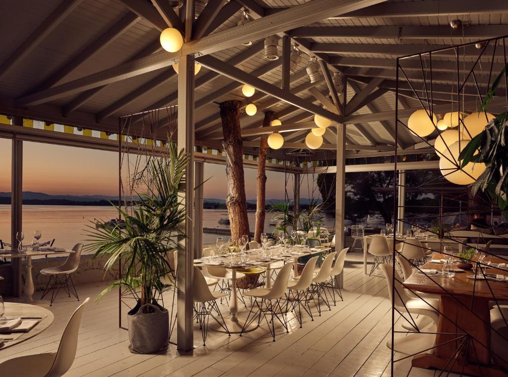 a dining room with tables and chairs on a patio at Ekies All Senses Resort, a Member of Design Hotels in Vourvourou