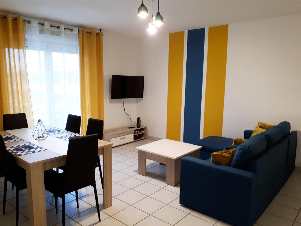 ein Wohnzimmer mit einem Tisch und einem blauen Sofa in der Unterkunft Le Venise - Gare Matabiau - T3 - avec Parking Privé in Toulouse