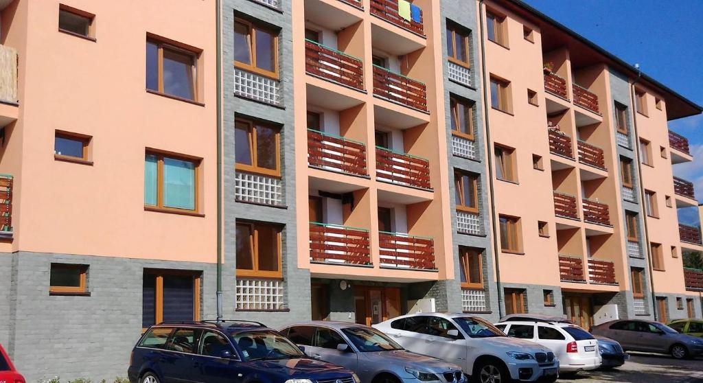 duży budynek apartamentowy z samochodami zaparkowanymi przed nim w obiekcie Apartmán Tatry Tatranská Štrba w mieście Tatranska Strba