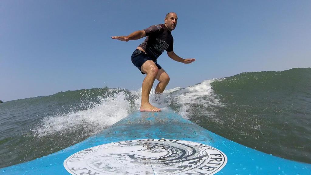 um homem a surfar uma onda numa prancha de surf no oceano em My Friend Surf Hostal em Trujillo