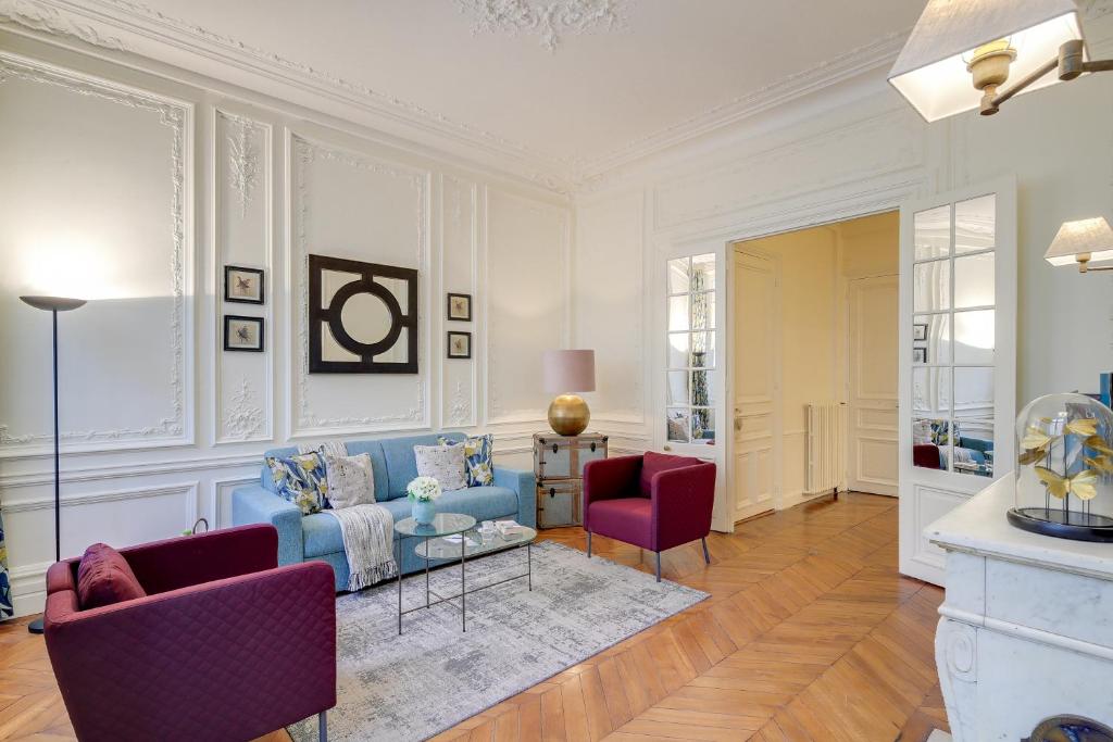 een woonkamer met een blauwe bank en 2 rode stoelen bij Sweet Inn - Messine in Parijs