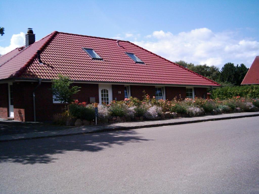 a house with a red roof and flowers on the street at FeWo Pülsen in KÃ¶hn