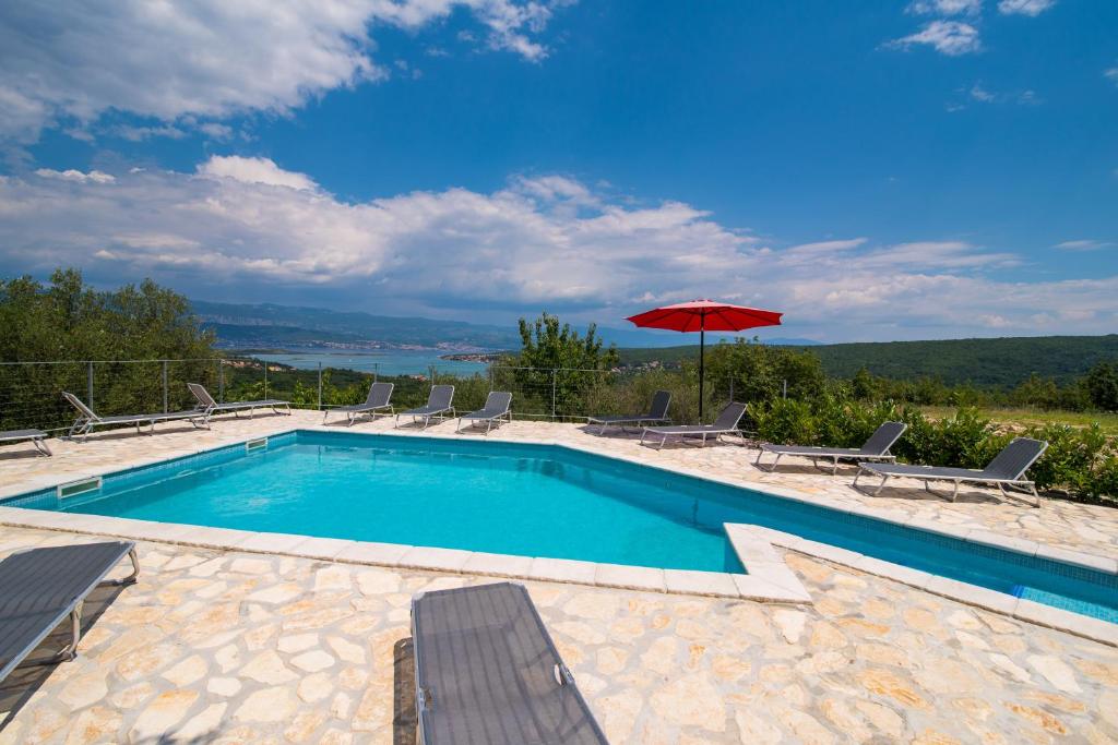 a swimming pool with chairs and an umbrella at Holiday apartment Angelina with Seaview and swimming pool in Sužan