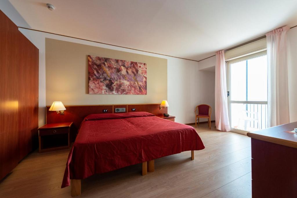 um quarto com uma cama vermelha e uma grande janela em Hotel Torre Normanna em Altavilla Milicia