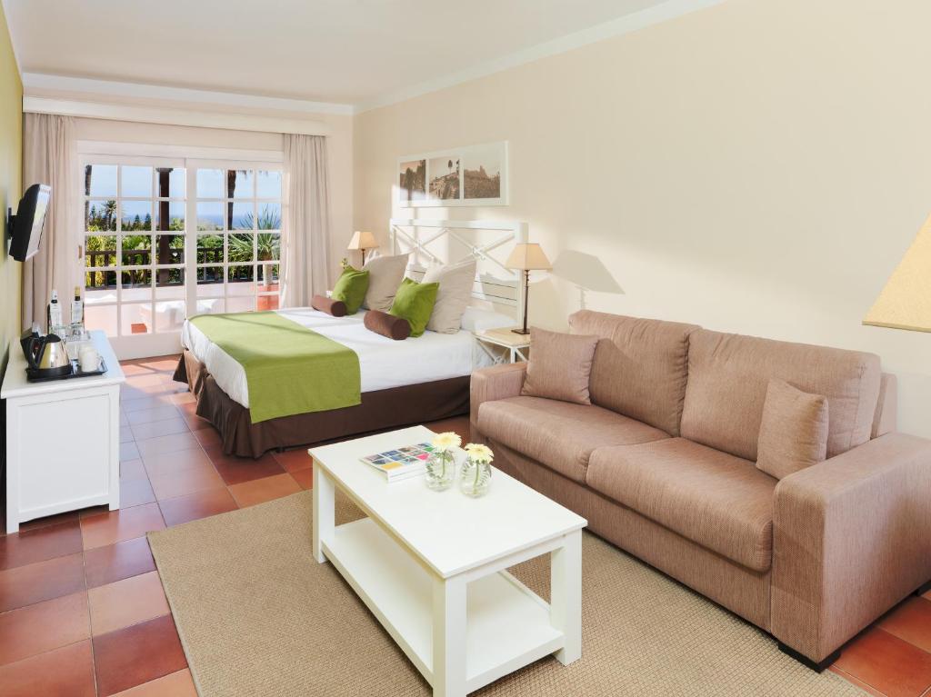 a living room with a bed and a couch at Hotel Jardín Tecina in Playa de Santiago
