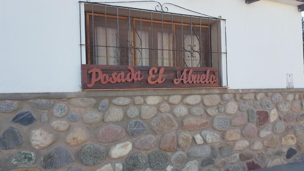 a window with a sign on a stone wall at Posada El abuelo in Molinos