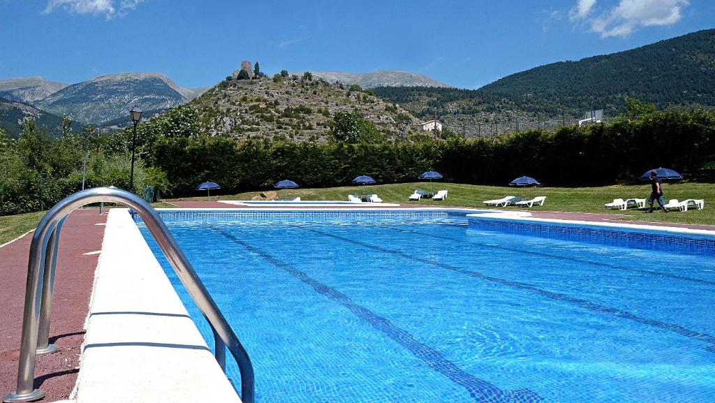 a swimming pool with a mountain in the background at Camping Cadí Vacances & Spa in Gósol