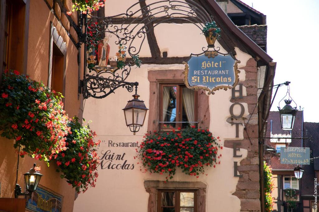 a building with a clock on the front of it at Hôtel le Saint Nicolas in Riquewihr
