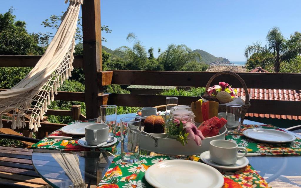 uma mesa com pratos e um cesto de comida em Pousada Bungalow na Praia do Rosa