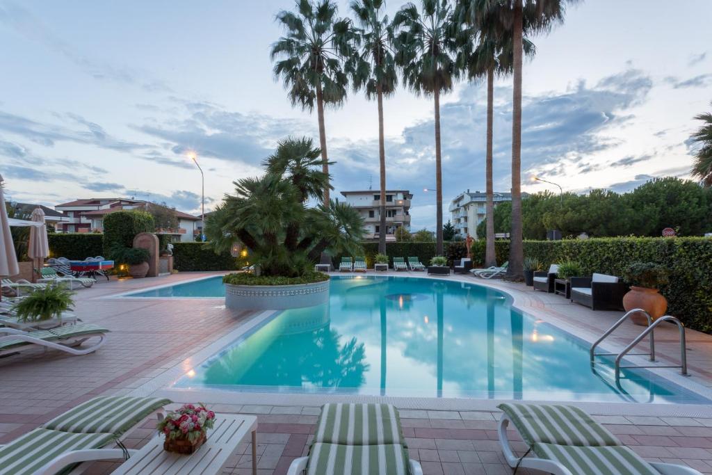 阿爾巴·阿德里亞蒂卡的住宿－Residence Torre Del Mar，一座棕榈树大型游泳池,配有躺椅