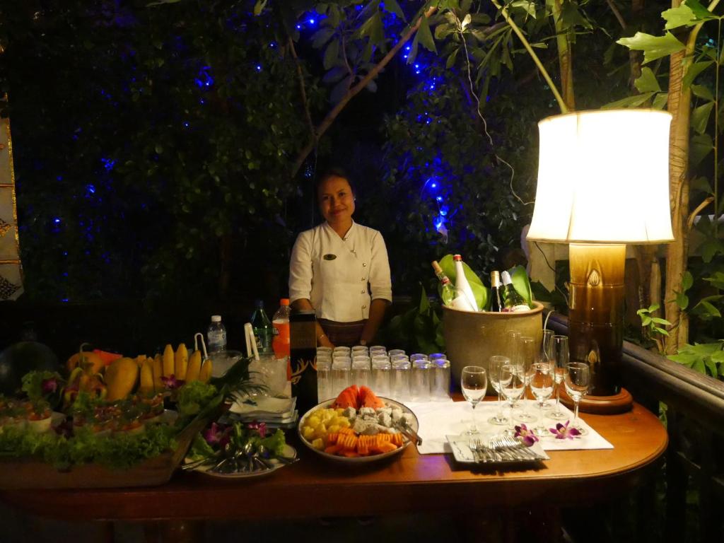 An evening food and drinks buffet arranged outdoors beneath garden lighting.