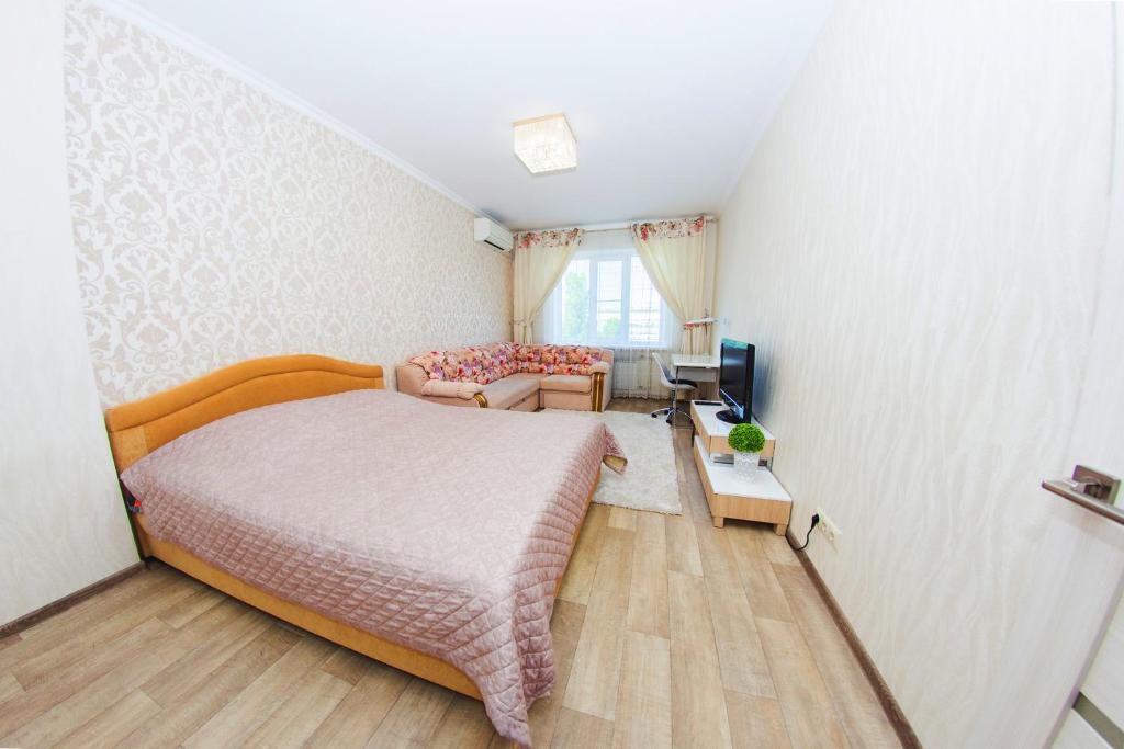 um pequeno quarto com uma cama e uma televisão em ATLANT Apartments 99 em Voronezh