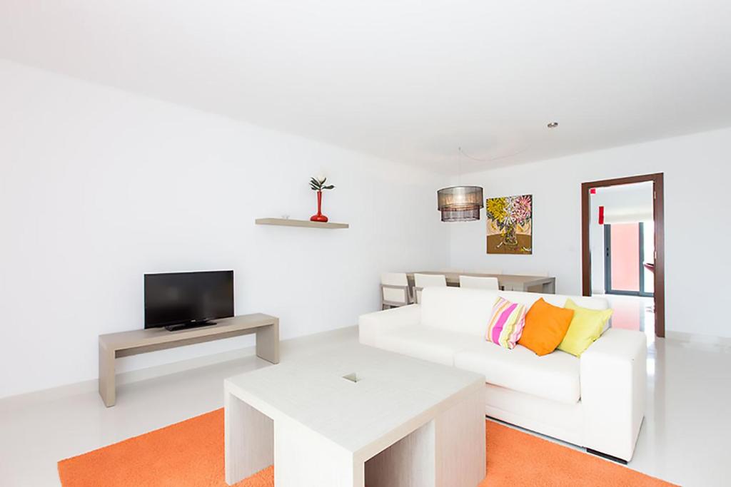 a white living room with a white couch and a tv at D Wan Deluxe Apartments in Baleal