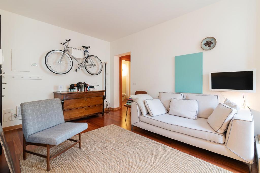a living room with a white couch and a bike on the wall at Scrovegni Design Apartment in Padova