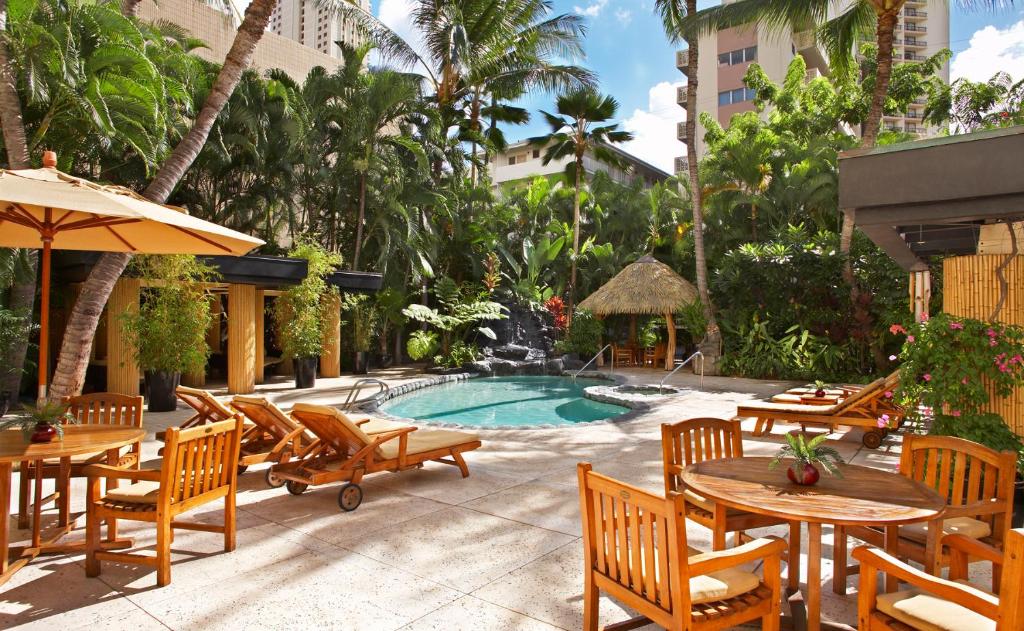a patio area with chairs, tables and umbrellas at Castle Bamboo Waikiki Hotel in Honolulu