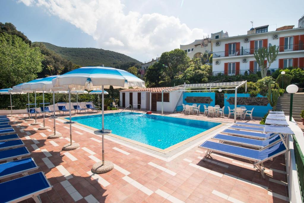 una piscina con sedie e ombrelloni accanto a un edificio di Hotel Bagnitiello a Ischia