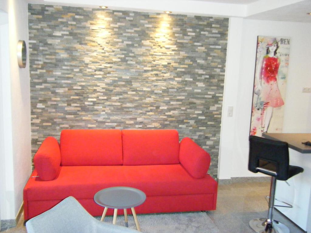 ein rotes Sofa in einem Zimmer mit Ziegelwand in der Unterkunft Wiethegers Ferienwohnungen Gästehaus Centrum II in Willingen