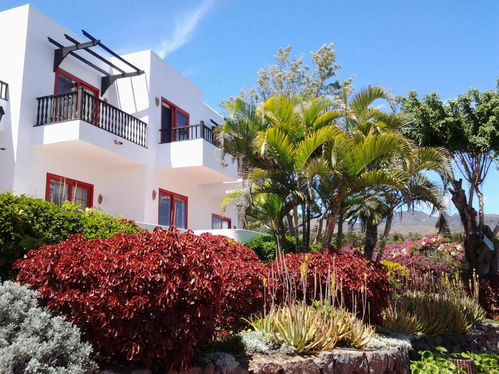 a white building with trees and plants in front of it at Hotel Jardín Tecina in Playa de Santiago