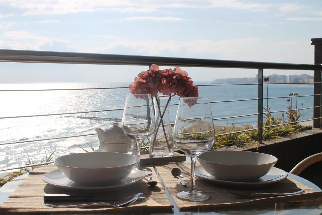 einen Tisch mit Tellern und Weingläsern sowie Blick auf das Wasser in der Unterkunft Sur Suites Buena Vista in Fuengirola