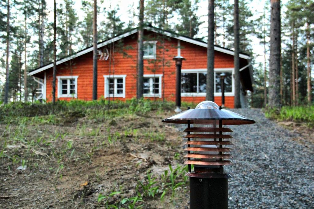 a small red house in the middle of a forest at Kultajärvi Holiday Home in Rastinniemi