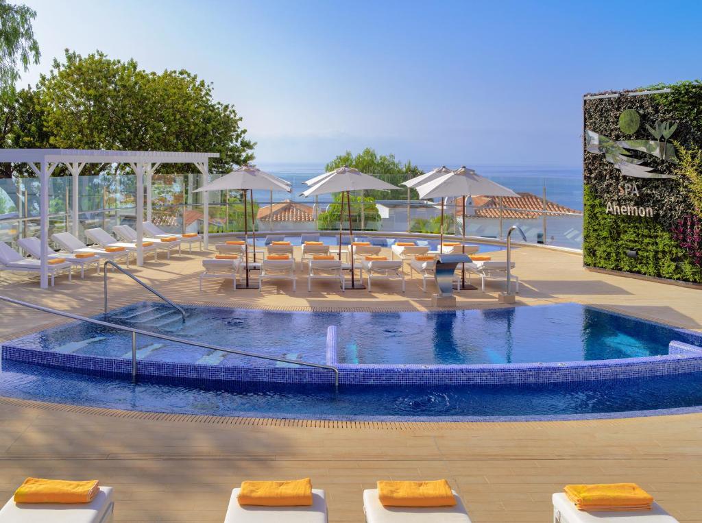 a swimming pool with chairs and umbrellas at Hotel Jardín Tecina in Playa de Santiago
