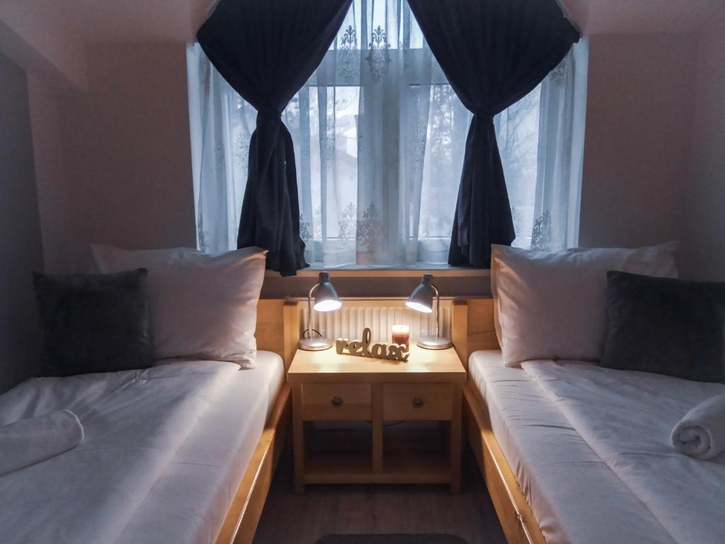 a bedroom with two beds and a window with curtains at Bloom Inn in Niš