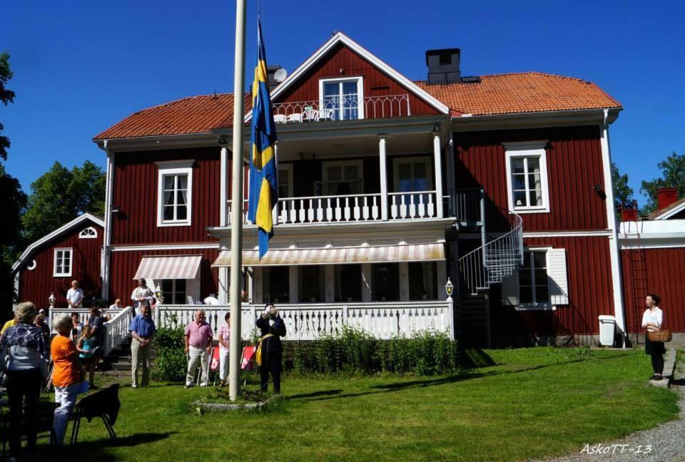 Une grande maison rouge avec des gens debout devant elle dans l'établissement Kolbäcks Gästgivaregård, à Kolbäck
