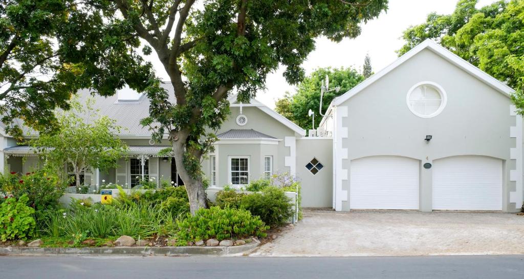 a white house with a tree and a garage at Laurel Cottage in Franschhoek