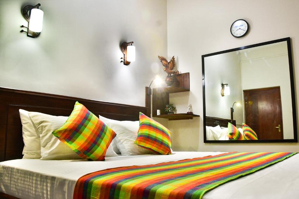 a bed with colorful pillows and a large mirror at Villa Hikka 08 in Hikkaduwa