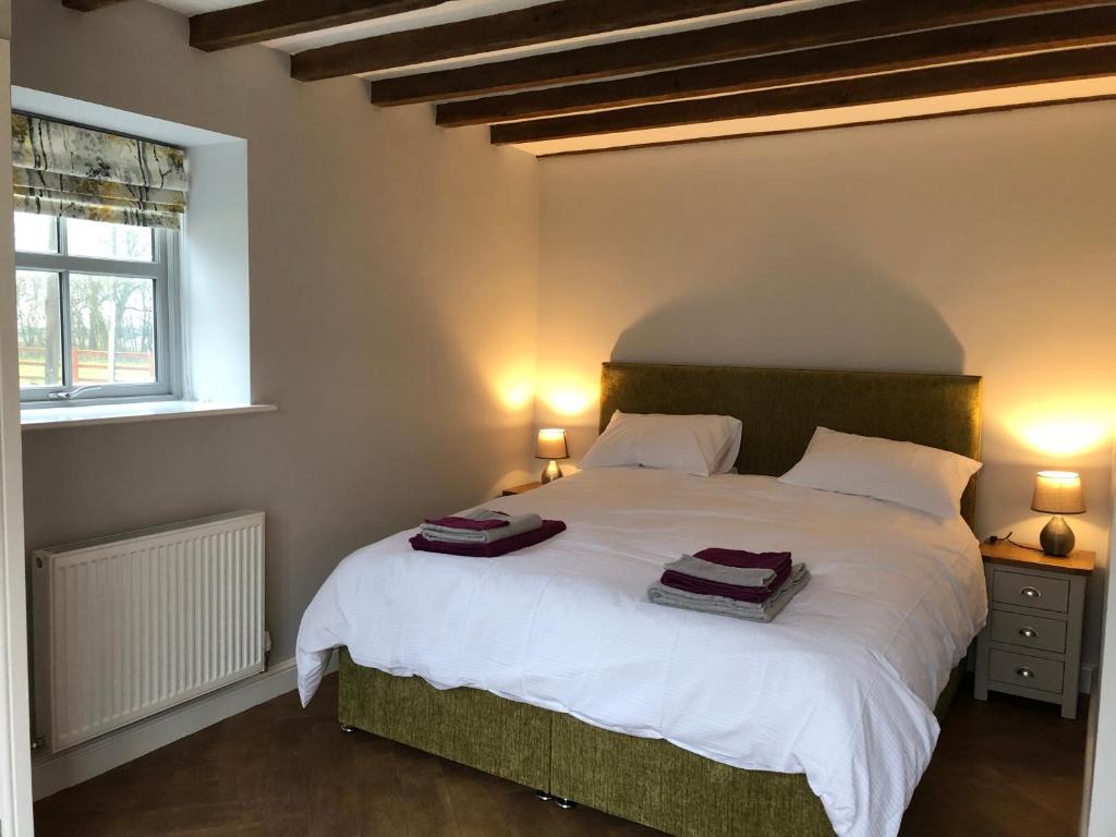 a bedroom with a large bed with two towels on it at Nellies Shed, Wolds Way Holiday Cottages, 3 bed spacious cottage in Cottingham