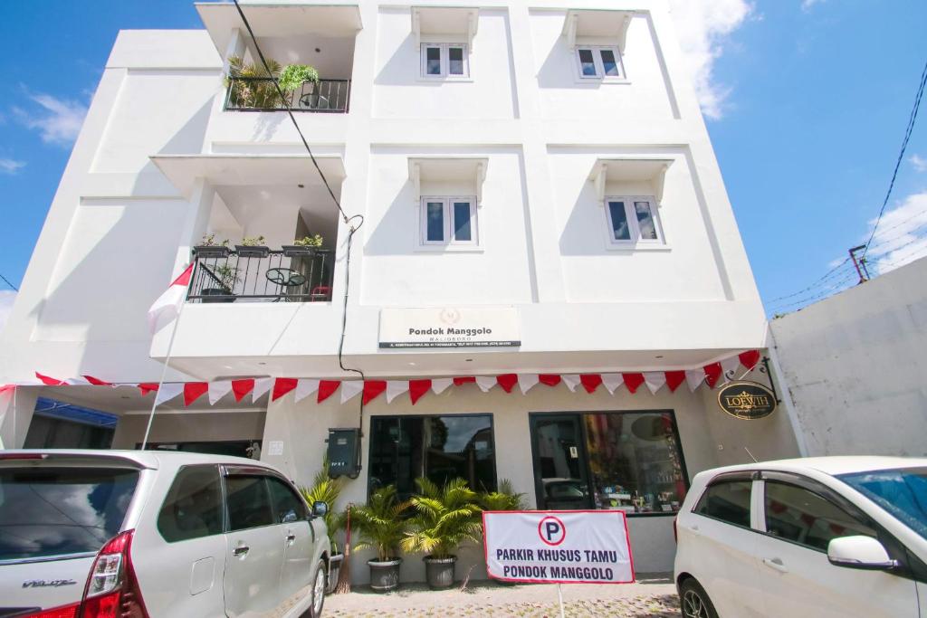 a white building with cars parked in front of it at Manggolo Homestay Syariah in Yogyakarta