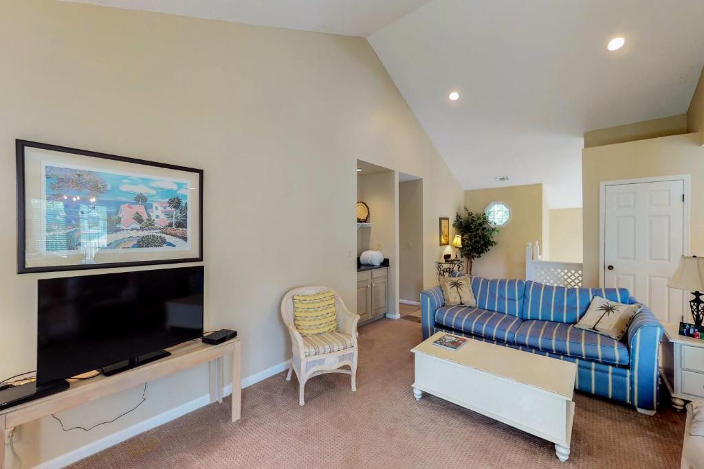 a living room with a blue couch and a tv at Evian 285 in Hilton Head Island