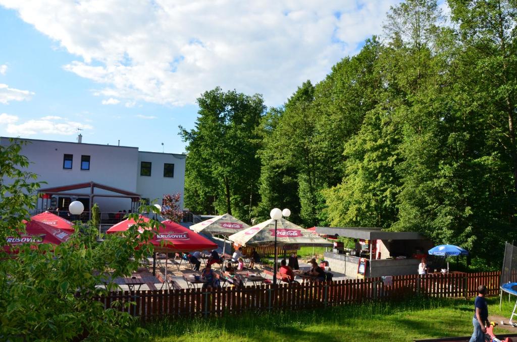 grupa ludzi siedzących w parku z parasolami w obiekcie Restaurace a penzion Zděná Bouda w mieście Hradec Králové