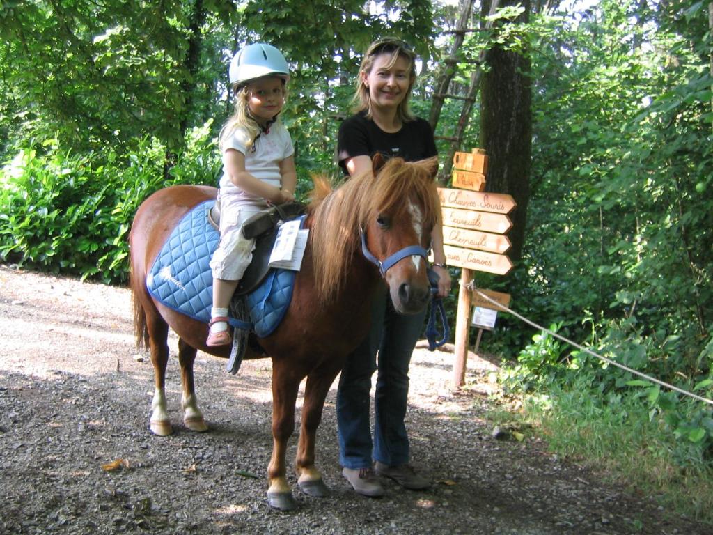 a woman and a child sitting on a horse at Les Ecolodges de l&#39;Orbière in Forcé