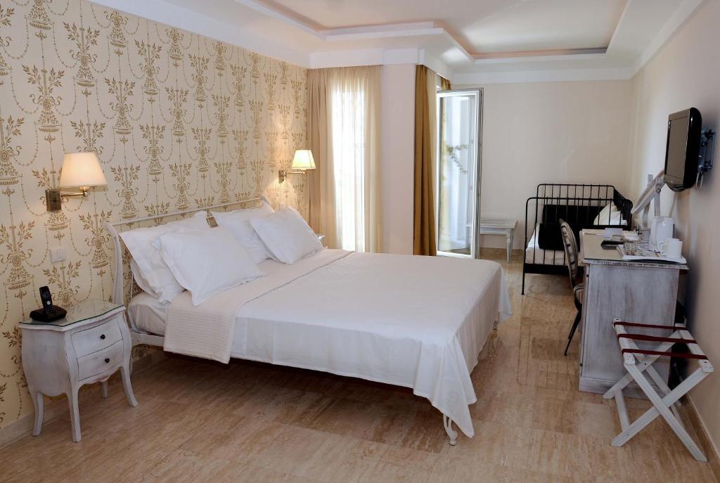 a bedroom with a large white bed and a desk at Hotel Azimut in Sveti Stefan