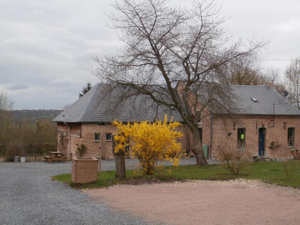 un edificio de ladrillo con un árbol delante de él en Chambre d'hôtes L'Ermite en Saint-Algis