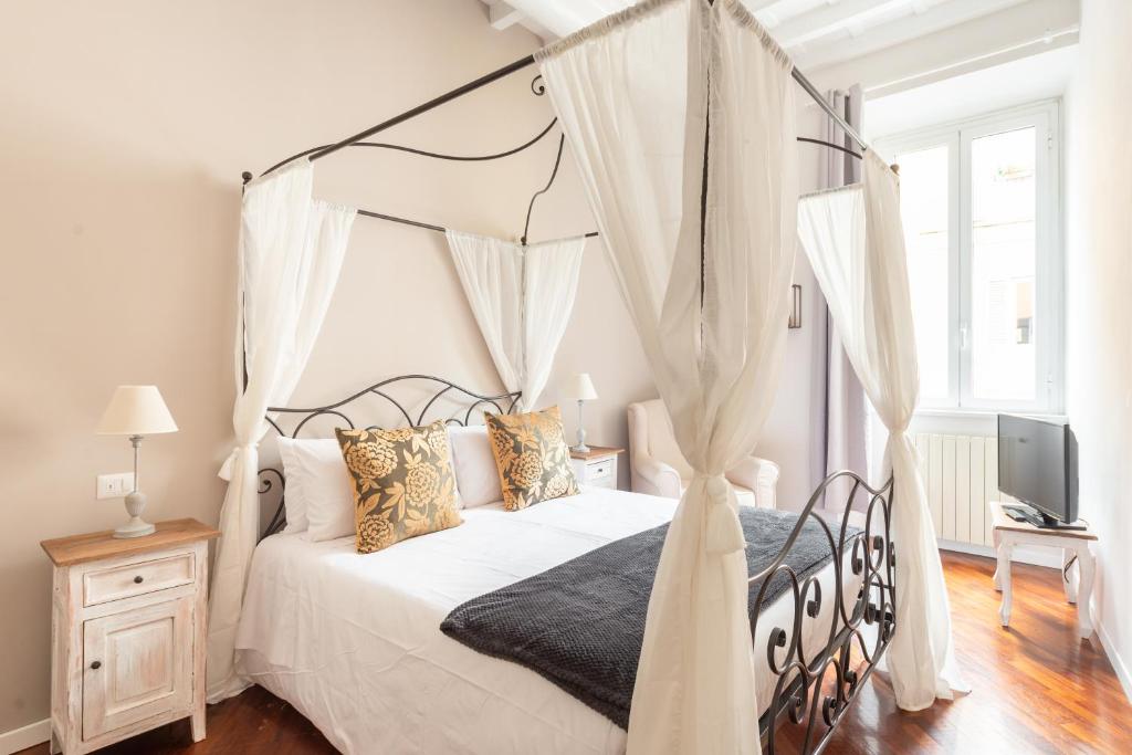 um quarto com uma cama de dossel e uma televisão em SuityRHome RioneMonti56 em Roma