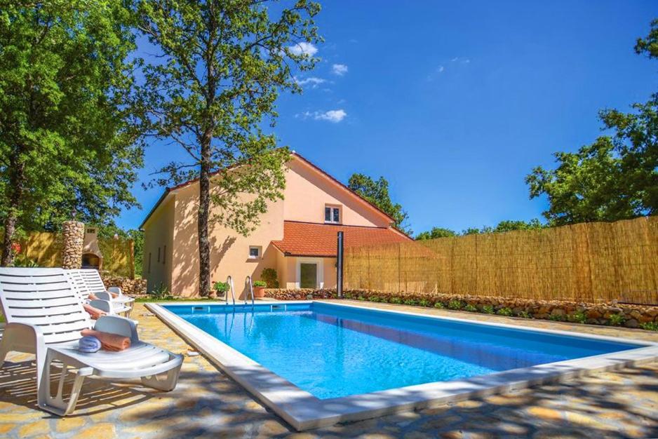 - une piscine avec 2 chaises et une clôture dans l'établissement Villa Lovro in Imotski, private pool, à Gornji Vinjani