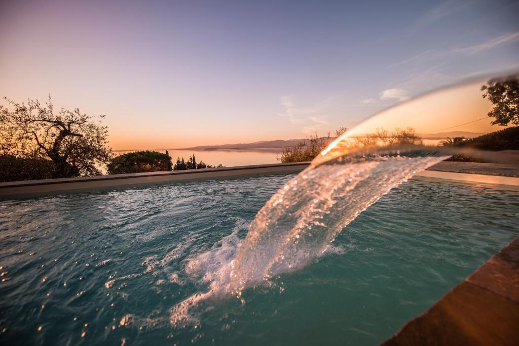 una piscina con una fuente de agua en el primer plano en Bianca la Luna amazing villa lakeside view, en Magione