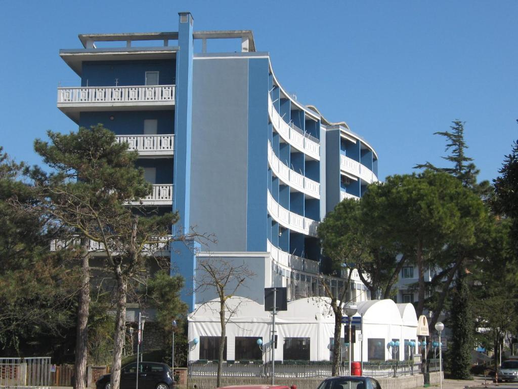 een blauw gebouw met bomen ervoor bij Residenza Sporting in Lignano Sabbiadoro