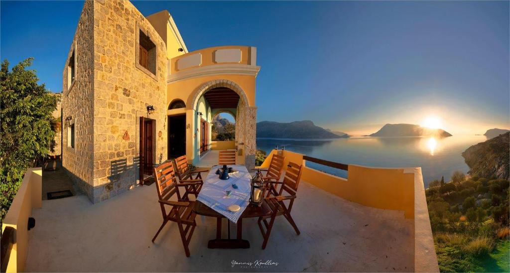 カリムノスにあるSecret Paradise Beach Villaのテーブルと椅子、水辺の景色を望むバルコニー