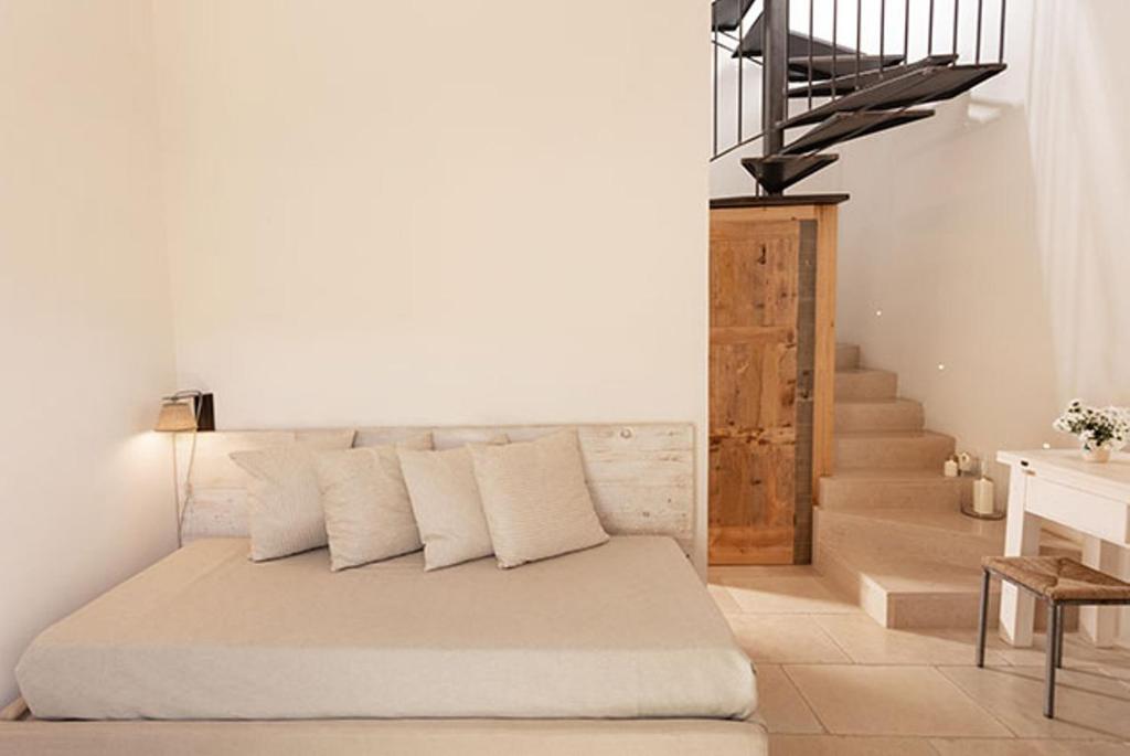a bedroom with a bed with white pillows and a staircase at Masseria Mongiò dell'Elefante in Otranto