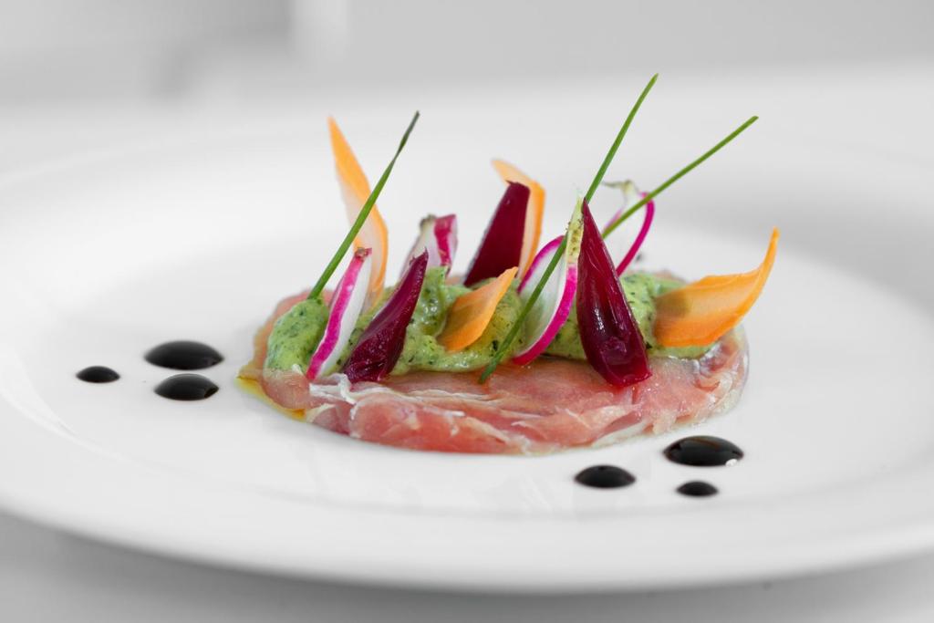 a piece of meat with vegetables on a white plate at Masseria Mongiò dell'Elefante in Otranto