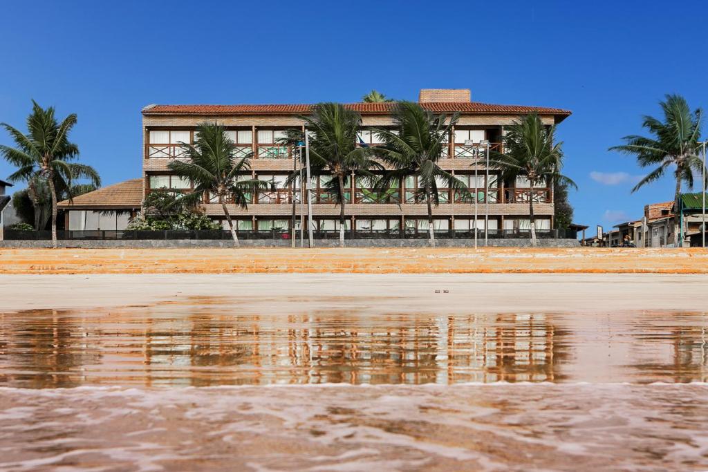 un edificio en la playa con su reflejo en el agua en Hotel Areias Belas en Maragogi