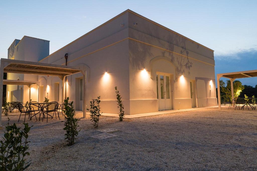 a white building with tables and chairs in front of it at Masseria Mongiò dell'Elefante in Otranto
