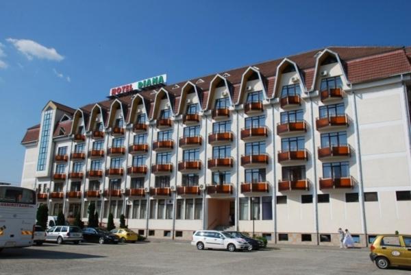 un bâtiment d'hôtel avec des voitures garées dans un parking dans l'établissement Hotel Diana, à Bistriţa