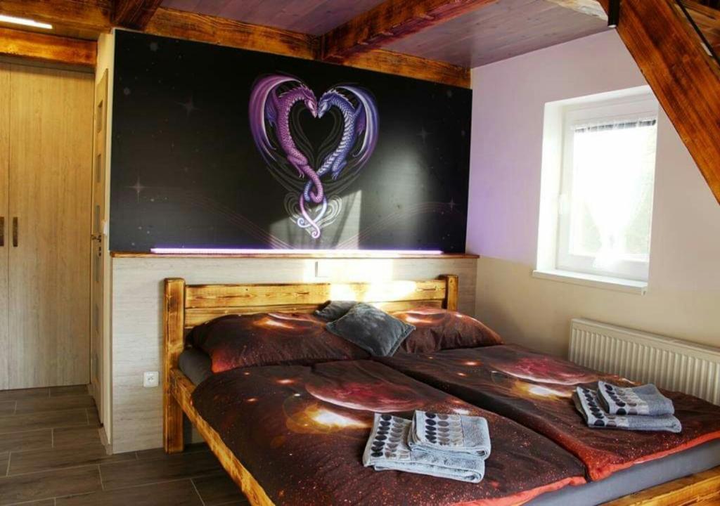 a bedroom with a bed with a purple heart on the wall at Apartmán Dračí údolí in Trutnov