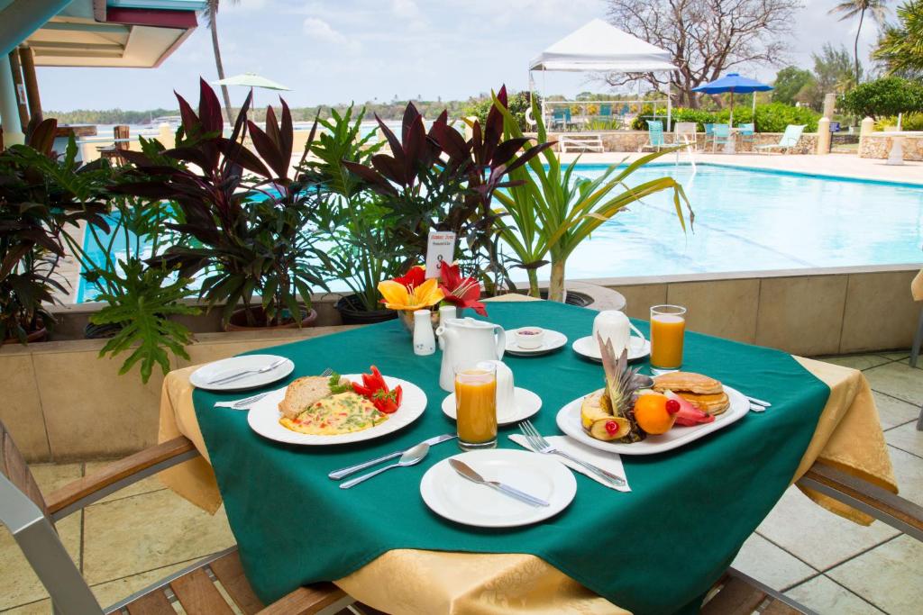 a table with plates of food on it next to a pool at Crown Point Beach Hotel in Crown Point