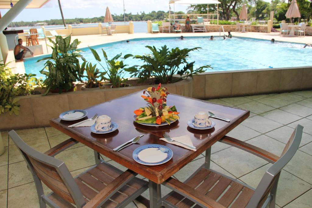 a table with a bowl of fruit on it next to a swimming pool at Crown Point Beach Hotel in Crown Point